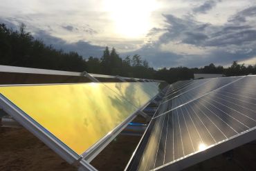 Solar panels reflecting sunlight on a partly cloudy day.