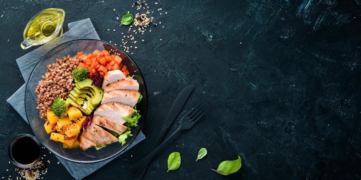 Healthy meal bowl with chicken, avocado, and vegetables.