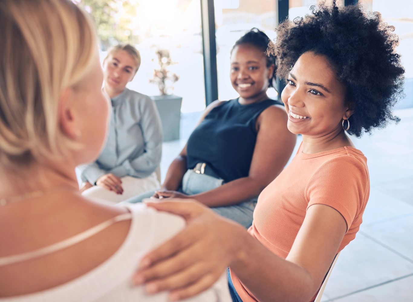 Diverse women engaging in a warm, supportive group conversation.