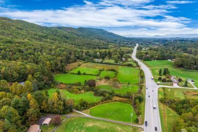 A scenic highway through green fields and wooded hills.