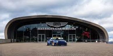 Front view of America's Car Museum with a blue sports car.