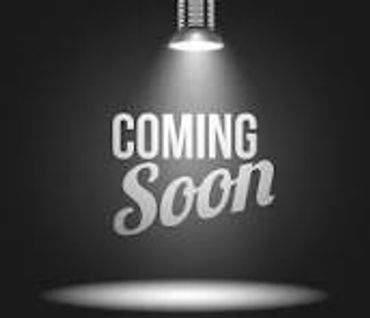 A spotlight shines on the text 'Coming Soon' against a dark background.