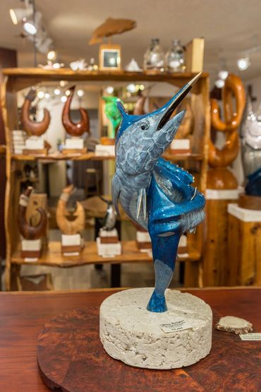 Blue marlin sculpture on a fossil coral base displayed inside Wirth Gallery.