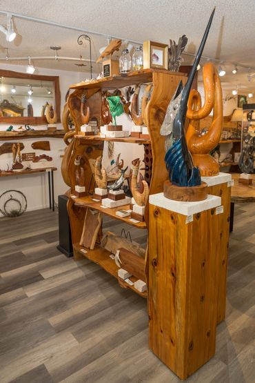 Blue sailfish sculpture displayed beside handcrafted fish hook sculptures on rustic wood shelving.