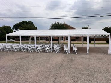 White chairs under a large white tent outside for Meals on Wheels event in McKinney, Texas.