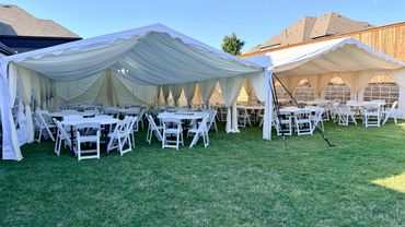Two white event tents set up, one of the tents with draped also with tables and chairs.