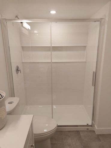 Modern white bathroom with glass shower and toilet.