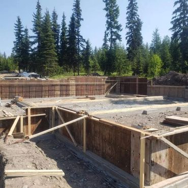 Wooden framework set up for concrete foundation in a forested area.