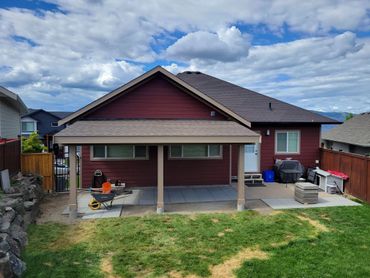 Backyard view of a house with a cloudy blue sky and construction tools.