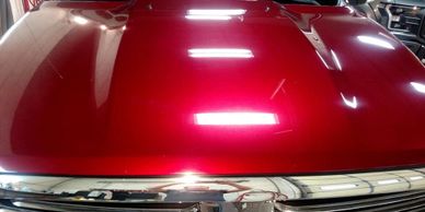 Shiny red hood on a pickup that has been treated with Flight Shield Sapphire V1 Paint Treatment