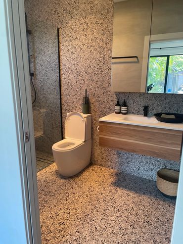 Modern bathroom with terrazzo tiles and wooden vanity.