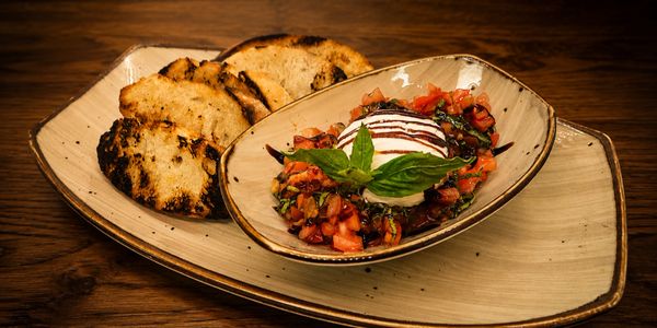 Grilled bread served with a fresh tomato and basil bruschetta topped with mozzarella.