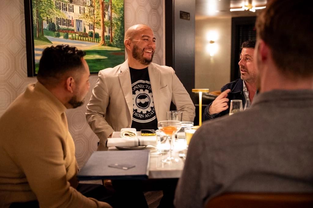 Four men engaged in lively conversation at a dinner table.