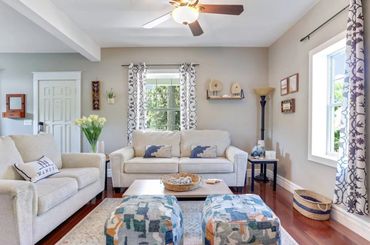 Bright and cozy living room with neutral sofas and patterned ottomans.