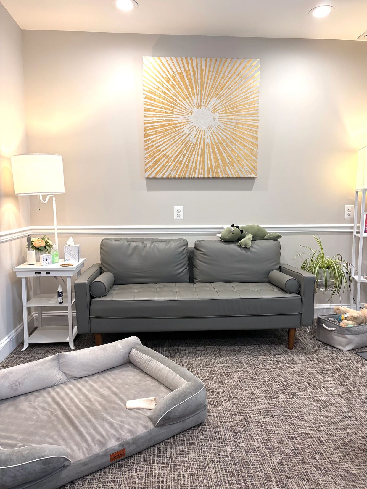 Modern living room with gray couch and sunburst wall art.