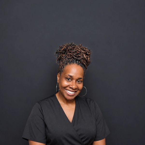 Smiling woman with braided hair in a black top.