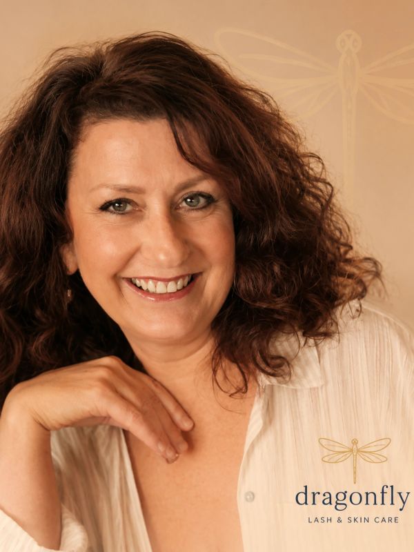 Smiling woman with curly hair promoting Dragonfly Lash & Skin Care.