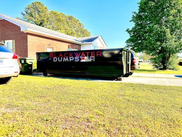 Blackwater Dumpster container placed near a suburban house on a sunny day.