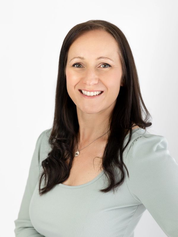 Smiling woman with long dark hair and light green top.