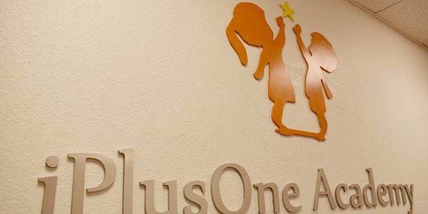 Signage of iPlusOne Academy on a wall.