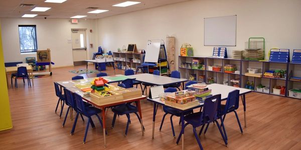 Empty classroom with children's furniture and educational materials.