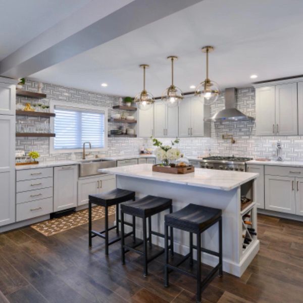 Modern white kitchen with island and pendant lights.