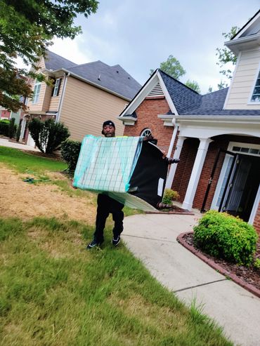 Mover from Grab And Go Movers in Atlanta, GA carrying large chair in front yard of home.