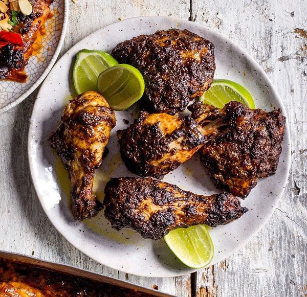 Grilled chicken pieces with lime wedges on a plate.