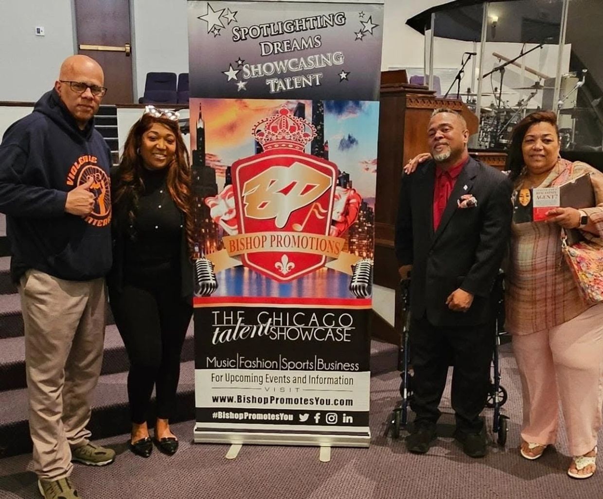 Four people posing beside a promotional banner for Chicago talent showcase.