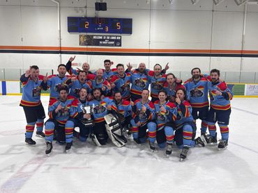 Hockey team posing with a trophy on ice rink after winning.