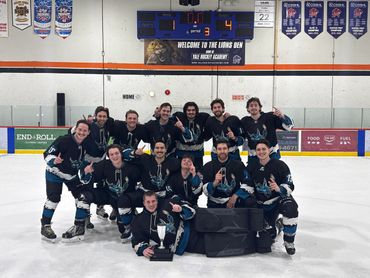 A victorious hockey team poses on ice with trophies and smiles.