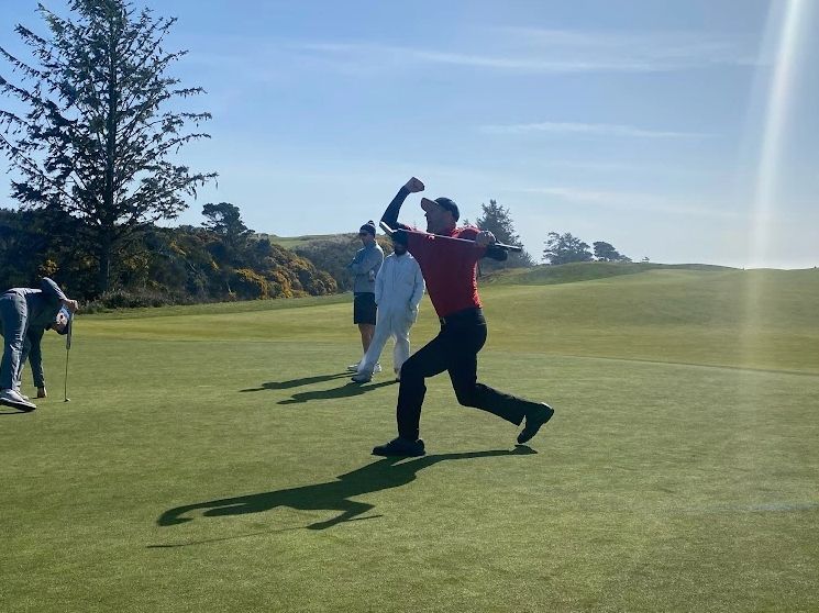 Golfer celebrates a successful shot on a sunny golf course.