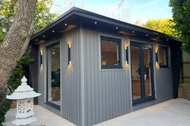 Modern garden office with gray cladding and ambient lighting.