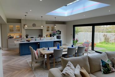 Modern open kitchen and dining area with skylight and garden views.