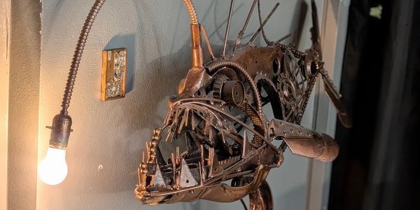 Metal fish sculpture with light bulb in its mouth.