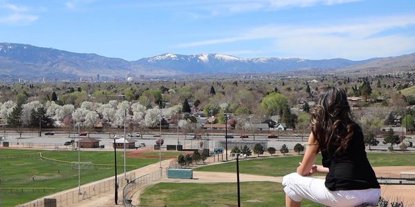 A woman overlooks a scenic cityscape with mountains in the background.