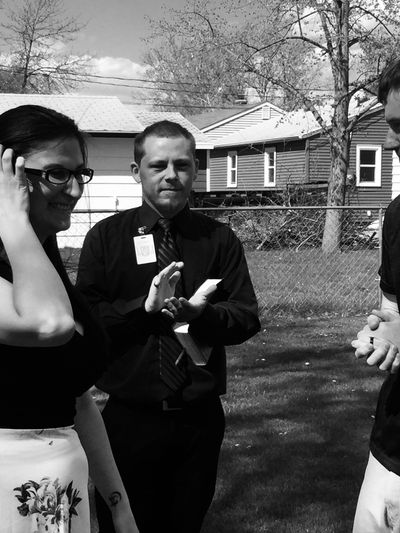 Three people engage in a conversation outdoors on a sunny day.