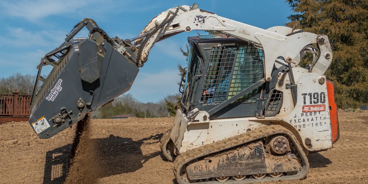 Excavator dumping dirt on a construction site under a clear blue sky.