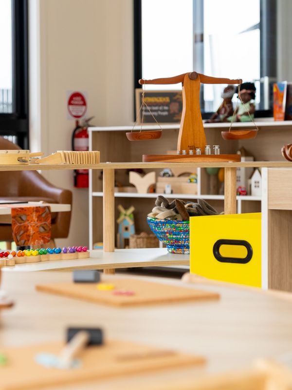 Wooden balance scale and colorful educational toys in a bright classroom.