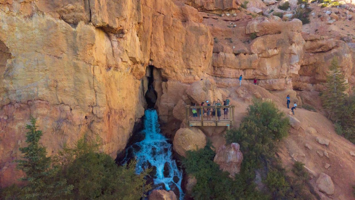 People observing a waterfall flowing from a canyon.