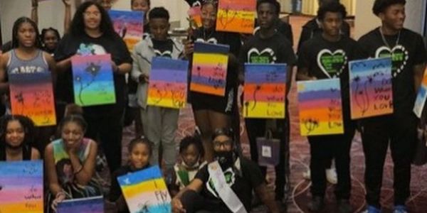 Group of young people holding colorful paintings with inspirational words.