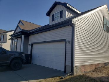Modern suburban house with a two-car garage and a black pickup truck parked outside.