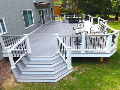 Spacious gray deck with black and white railing and outdoor seating.