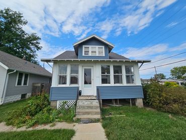 A blue and white house with a small porch and steps.
