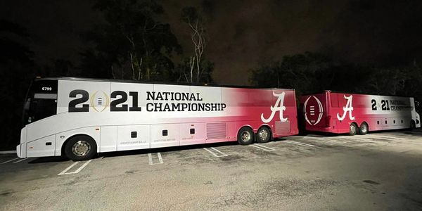 2021 National Championship team buses with Alabama logos parked at night.