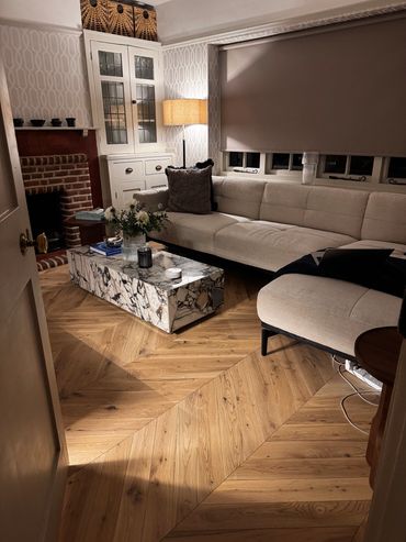 Cozy living room with beige sofa and marble coffee table on wooden floor.
