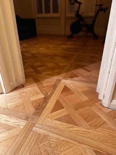 Intricate wooden parquet flooring leading into a dimly lit room.