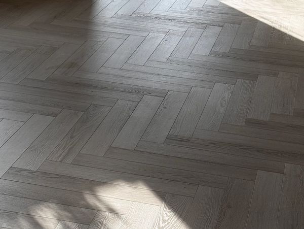Sunlight casts soft shadows on a herringbone-patterned wooden floor.