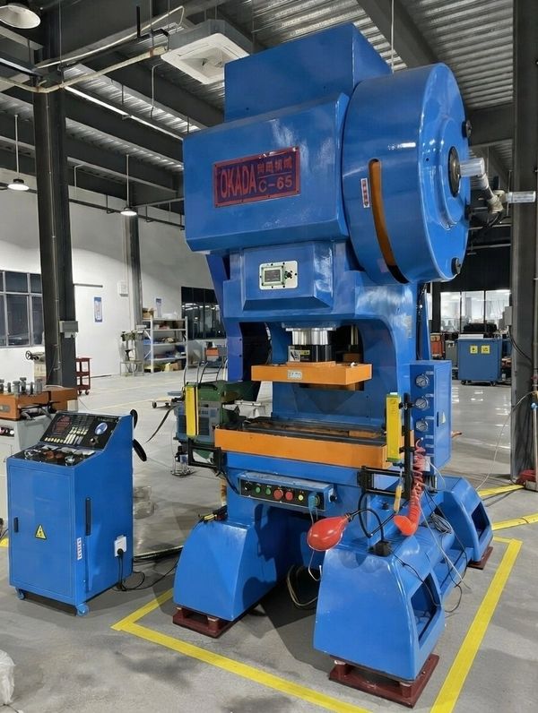 Large blue Okada C-65 industrial press machine in a factory setting.