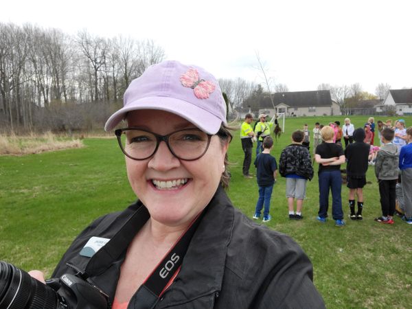 Selfie of Jackie Krull with a camera in front of a group of kids